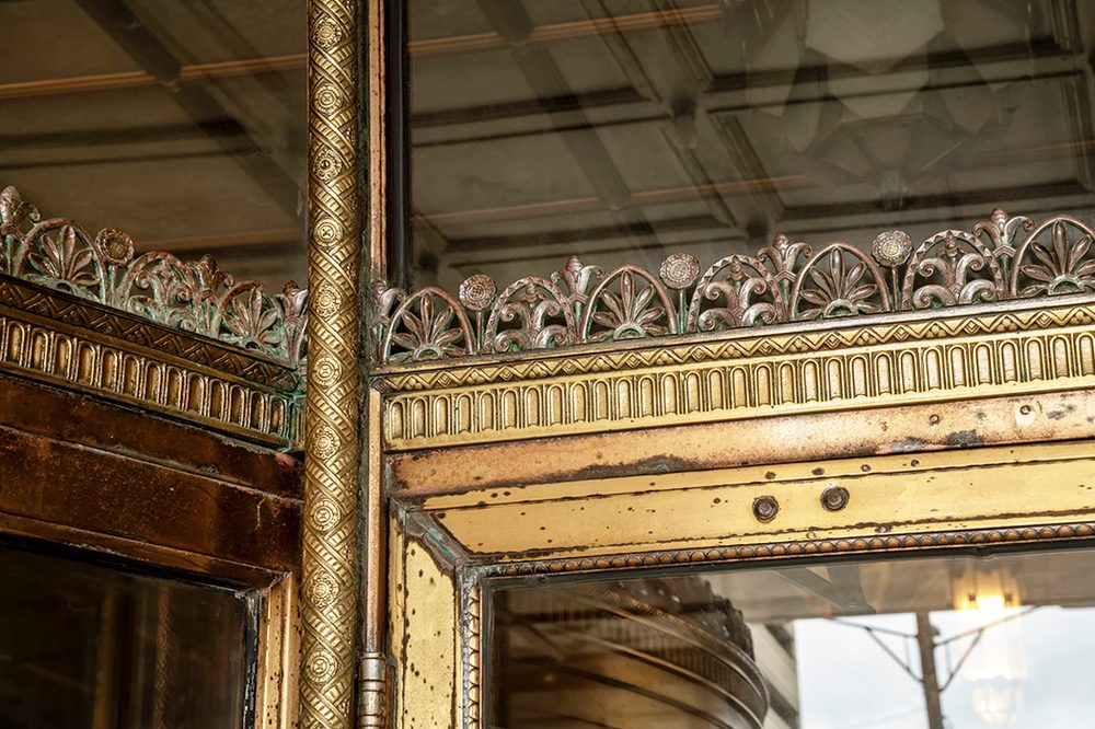 Bronze thistle frieze and saddle-and-rope detail on a storefront entrance before restoration